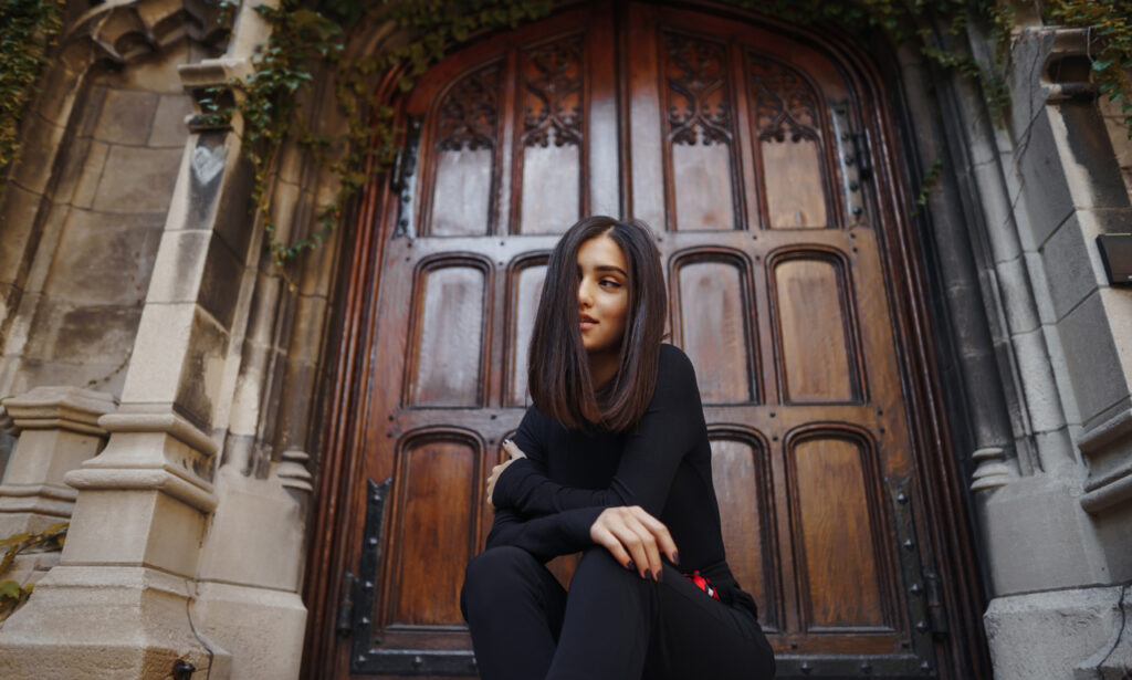 Model wearing dark academia fashion outfit with vintage coat and books